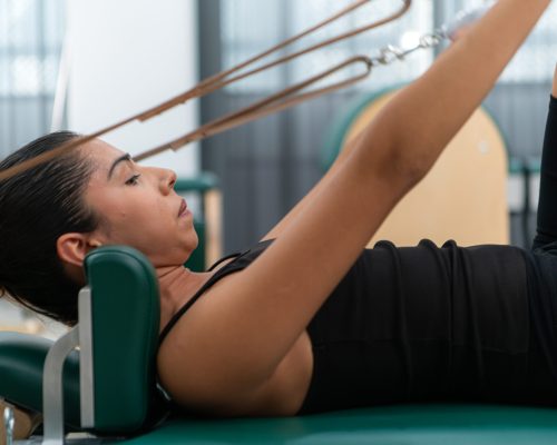 A young woman doing pilates exercises on a pilates reformer